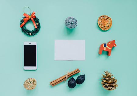 Creative flat lay of christmas ornaments in minimal style with blank greeting card on green backgroundの写真素材