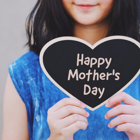 Young asian girl holding blackboard heart with Happy motherâs day word の写真素材