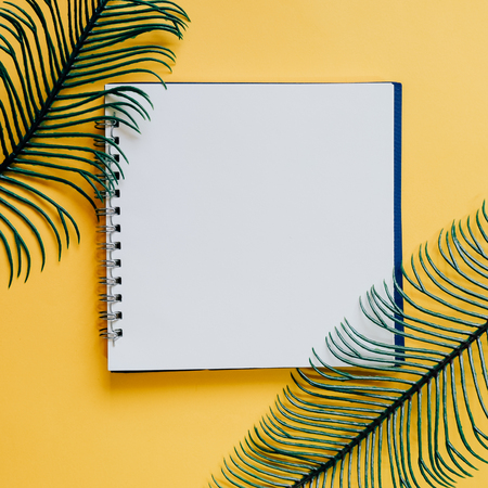 Flat lay of minimal workspace blank notebook with green plant on yellow background, spring and summer conceptの写真素材