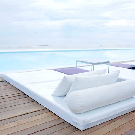 Modern beach bed on swimming pool deck in resort, summer vacation conceptの写真素材