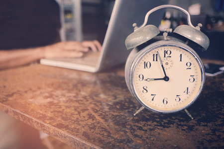 A business owner using laptop and working on time with clock on the table