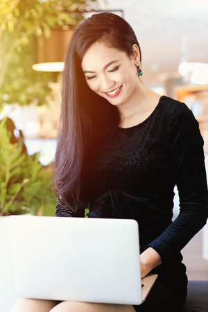 Young asian beautiful business woman smiling and using laptop in modern office, business and  people conceptの写真素材