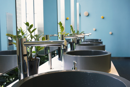 Modern silver faucet and wash basin with green plant in luxury bathroom hotelの写真素材