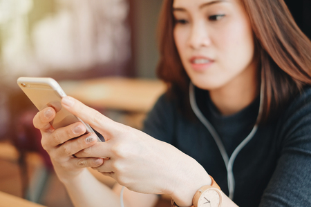 Young asian woman playing music with her smartphone and wearing earphones, lifestyle and technology conceptの写真素材