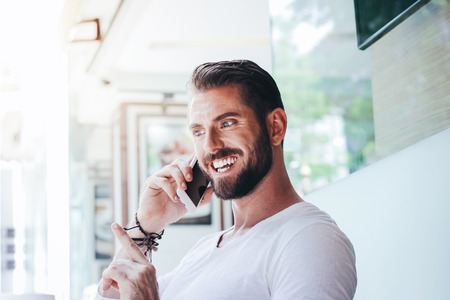 Happy businessman talking on the mobile phone in sidewalk cafeの写真素材