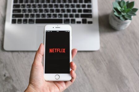 BANGKOK, THAILAND - April 28, 2018 : Close up hand holding iphone and showing Netflix app icon on screen. Netflix is an international leading subscription service for watching movies and TV series.のeditorial素材