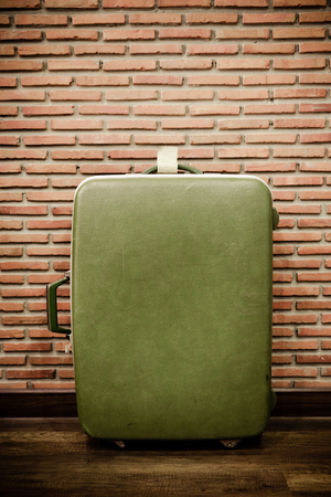 Old green luggage bag for travel with brick wall backgroundの写真素材
