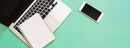 Creative flat lay design of workspace desk with laptop, blank notebook and smartphone with copy...