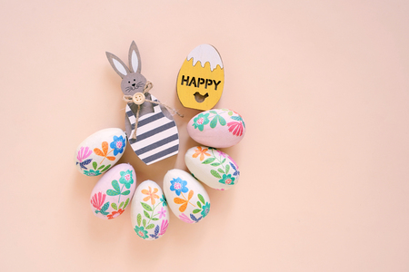 Happy Easter concept with wooden bunny and colorful easter eggs on yellow background. Top view with copy spaceの写真素材