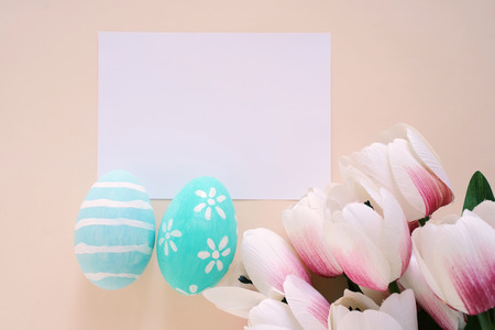 Happy Easter concept with blank card, colorful easter eggs and pink tulips. Top view with copy spaceの写真素材