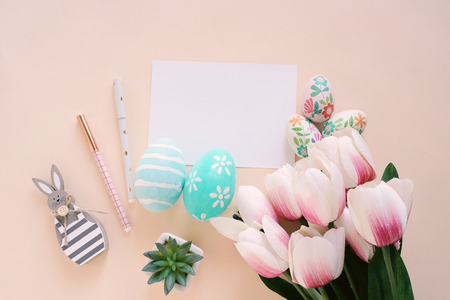 Happy Easter concept with blank card and colorful easter eggs and pink tulips. Top view with copy spaceの写真素材