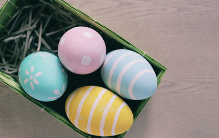 Pastel and colorful easter eggs in nest and basket on wooden background and copy space, happy easter holiday conceptの写真素材