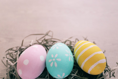 Pastel and colorful easter eggs on nest with wooden background and copy space, happy easter holiday conceptの写真素材