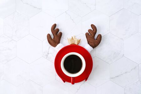 Flat lay of black coffee red cup with reindeer headband for christmas celebration on white marble background, holiday conceptの写真素材