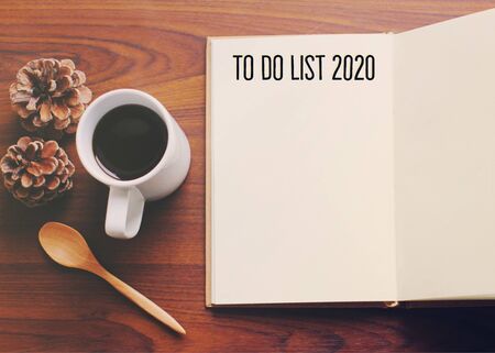 To do list 2020 on flat lay photo of workspace desk with coffee and notebook on table wooden background, new year resolutions conceptの写真素材