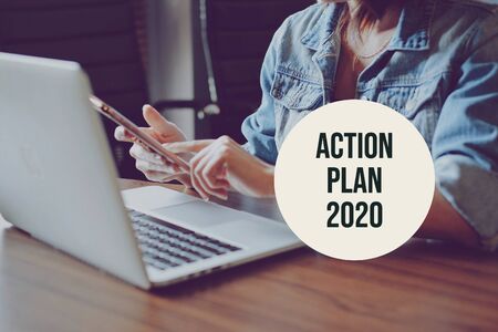 Action plan 2020 with young freelance woman using smartphone and laptop in modern workspace, new year resolution conceptの写真素材