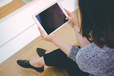 Young asian woman enjoy using tablet in modern office or shopping mall, technology and lifestyle conceptの写真素材