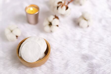 Cotton facial pads for removal makeup with natural cotton flowers and candle on white fur background, hygiene and healthy care lifestyleの写真素材