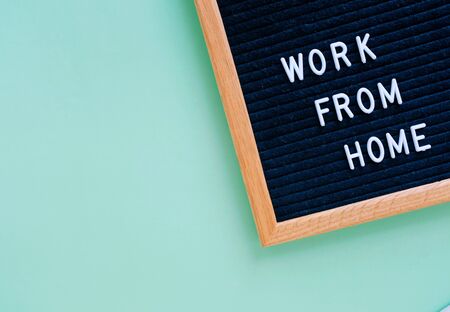 Flat lay of notice board with slogan message work from home on green background with copy space,...