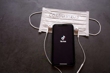 BANGKOK, Thailand - April 2, 2020 : Flat lay of iPhone XS showing Tik Tok application on screen with earphones and mask written with Coronavirus, Tik tok is popular social media network and entertainmentのeditorial素材