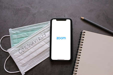BANGKOK, Thailand - April 2, 2020 : Flat lay of smartphone showing zoom application and mask with notebook. Zoom is popular cloud meeting or video conference during COVID-19 and Coronavirusのeditorial素材