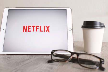 BANGKOK, THAILAND - April 28, 2018 : Netflix app on ipad tablet screen with eyeglasses and coffee...