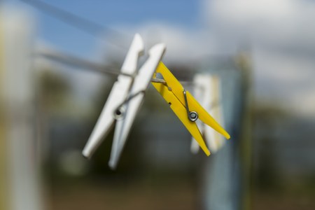Two colorful clothespin white and yellow on the white rope