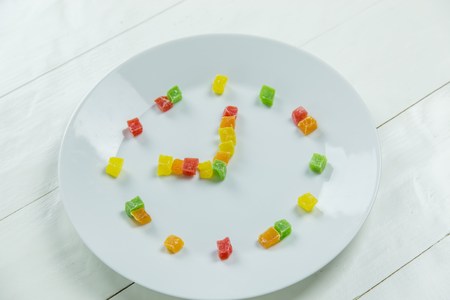 Fruit clock with candied fruits on wooden white backgroundの写真素材