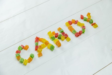 Sweet word with candied fruits on wooden white backgroundの写真素材