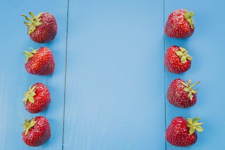 Fresh strawberries in a line on blue wooden backgroundの写真素材