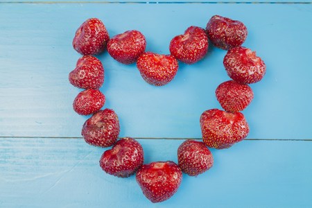 Strawberries with heart shape on wooden backgrondの写真素材