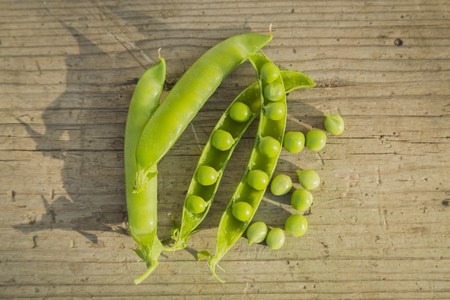 open pea pods on old wooden table