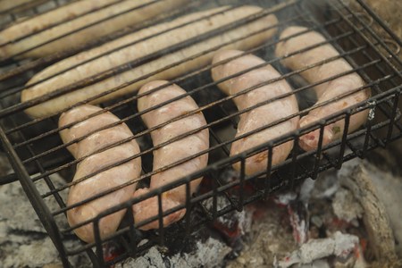 Tasty sausages on grill on nature, green backgroundの写真素材