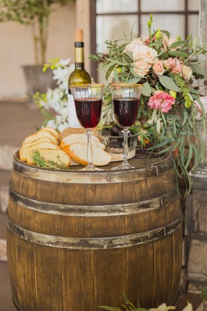 Black olives in glass vase, bread and vine, flowers on old oak barrel, wedding decorの写真素材