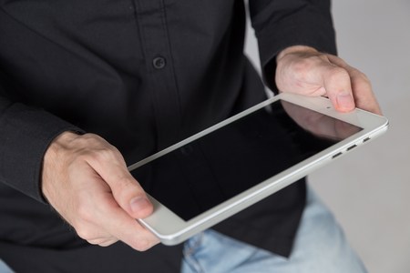 Young businessman holds tablet, watch video on tablet