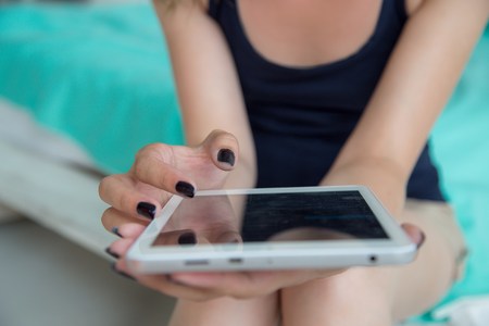 Close-up woman hands with black nails using digital tablet computer ipad touchscreen.の写真素材