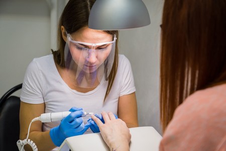 The master uses an electric machine to remove the nail polish during manicure in the salon. Hardware manicure. Concept of body careの写真素材