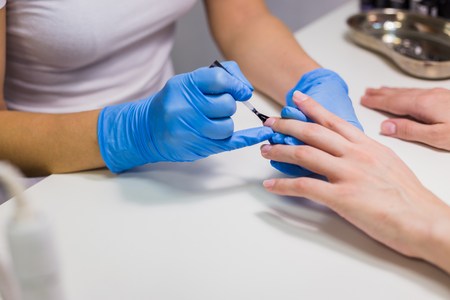 Professional beautician applying nail polish to female nail in a nail salon.の写真素材