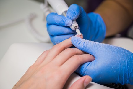 Closeup shot of master uses an electric machine to remove the nail polish during manicure in the salon. Hardware manicure. Concept of body careの写真素材