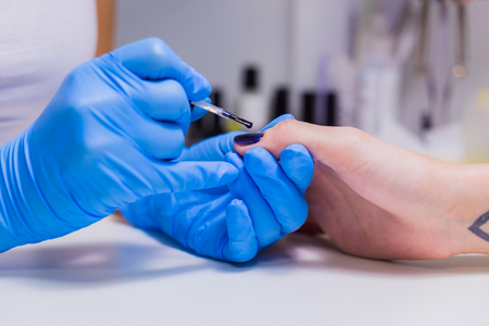 Nails painting with brush in nail salon on woman handsの写真素材