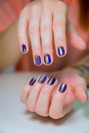 Finished purple shellac manicure, woman in nail beauty salon. Hands lie on white table and show the beautiful manicureの写真素材