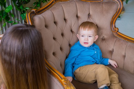Little happy boy sitting on the chair at homeの写真素材