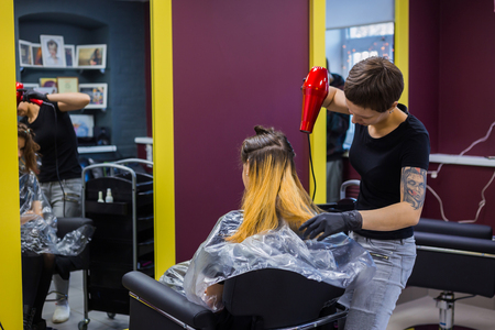 Professional hairdresser, stylist drying client hair with blow-dryer at salon, studio. Beauty and haircare conceptの写真素材