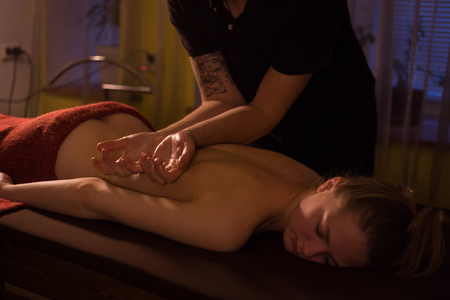 Professional male masseur doing back massage for female client in spa center, studio. Wellness, harmony, relaxation and healthcare conceptの写真素材