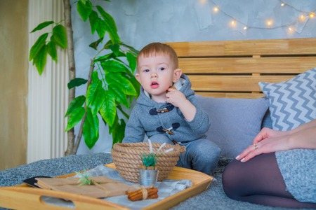 Happy young mother and her baby son playing with walnuts on the bedの写真素材