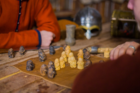 Two men in russian ethnic suit playing medieval popular strategy board game - tafl. Folk,...