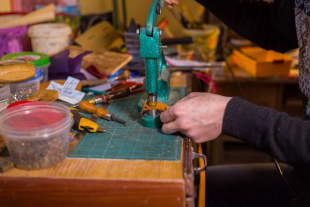 Professional male skinner, tanner working with genuine leather belt at workshop, studio. Handmade and leatherwork conceptの写真素材