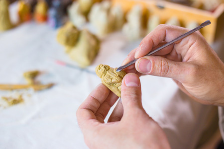 Professional male potter making clay figure for medieval popular strategy board game - tafl....