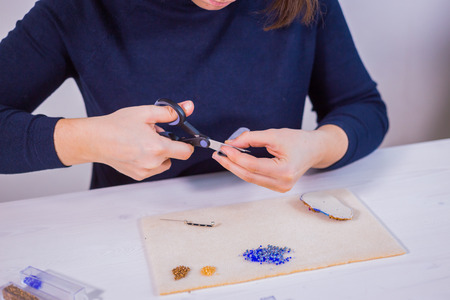 Professional jewelry designer making handmade brooch with beads in studio, workshop. Fashion,...