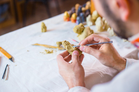 Professional male potter making clay figure for medieval popular strategy board game - tafl. Handwork, crafting and traditional arts conceptの写真素材